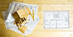 Building house. House construction. Many drawings for building, pencils and small wooden house on wooden background.