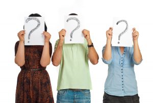 Three casual people standing in a line and holding questions marks isolated on white background